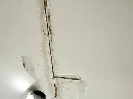 A water stain and crack running along a ceiling seam after a leak above